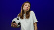 © Krakenimages.com - Woman holding soccer ball with puzzled expression against blue background, suggesting confusion or uncertainty in sports context.