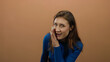 © Krakenimages.com - Woman in blue sweater whispers against a brown background, conveying a secretive gesture with expressive eyes and soft lighting.