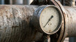 © MYKHAILO KUSHEI - An antiquated pressure gauge clings to a rusted metal pipe. The aged machinery hints at a bygone era of industrial endeavors and technological prowess.