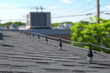 © noiteterna - Vista cercana de tejado con soportes cilíndricos negros que elevan cables eléctricos o de comunicación, junto a unidades HVAC y postes. Instalación técnica en entorno urbano con gestión eficiente.