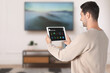 © New Africa - Smart home system. Man using app on tablet computer to control house features in room