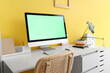 © Pixel-Shot - Modern computer with blank screen on table near yellow wall in home office, closeup