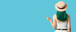 © Pixel-Shot - Pretty young woman with green hair in hat pointing at something on blue background, back view