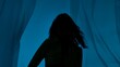 © kinomaster - Artistic silhouette of a woman with flowing hair, against a transparent plastic sheet with a blue background, evoking mystery.