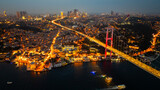 A breathtaking aerial night view of Istanbul showcasing the illuminated 15 July Martyrs Bridge (Bosphorus Bridge) stretching across the Bosphorus Strait. The city glows.