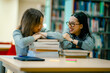 © Wanwajee - Happy learning portrait of university students with textbooks inside library expressing confidence education lifestyle