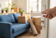 © Ajay - New homeowner opening door with house key in modern living room, moving boxes and plants, real estate concept.
