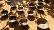 © Syahrul Studio - Arrangement of worn metal and clay cooking bowls scattered on a textured surface with dappled sunlight
