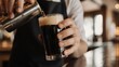 © Gaga - Bartender pouring a dark beer into a glass at a bar.