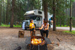 © unai - Family roasting marshmallows at campfire near camper van in banff national park