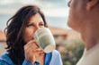 © Lomb - Middle aged woman coffee balcony home outdoor with blurred man in foreground - lifestyle serenity morning