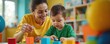 © Pete - Woman plays with boy using colorful blocks. Child develops skills during therapy session. Teacher helps toddler learn and grow in classroom. Early childhood education.