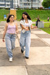 © Guillermo Spelucin - Two young women friends strolling in urban park