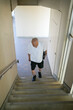 © Masakazu Tokashiki - A man wearing a white shirt and black shorts walks up a set of stairs. He is carrying a briefcase