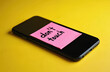© Maryna - Black smartphone with pink note sticker, inscription dont touch, digital detox concept. Yellow background, focus on phone screen, no gadget use reminder.