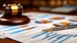 © Almadeena - Wooden gavel rests near financial report containing colorful charts and a professional writing instrument