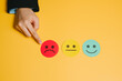 © JK_kyoto - Feedback concept. Unhappy red face emoji being pointed at by hand with neutral and happy face emojis nearby on yellow background