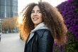 © ADDICTIVE STOCK - Portrait of a smiling woman with curly hair outdoors