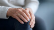 © Moddy - Age-Related Health Concerns: A close-up shot captures an elderly person, showcasing the tender hands delicately resting on the knee. this image tells a story of years lived.