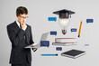 © Who is Danny - Businessman using laptop for online education with books, graduation cap, and communication icons on light background as concept of learning.