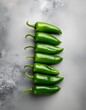 © MZARTT - A vibrant stack of green Hot and Spicy Food peppers arranged vertically on a grey textured background from a birds eye viewpoint.