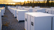 © A2Z AI  - A landscape view showcases a large array of white, modular energy storage units, bathed in the soft glow of the setting sun, promising sustainable power solutions.