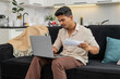 © Andrii Iemelianenko - Indian man at home enters bills in spreadsheet on laptop checks papers and uses calculator to verify total. Arabian guy on sofa reviews receipts updates table saves file and records budget result log