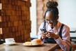 © Serhii - African girl taking a picture of a burger before eating in a cafe