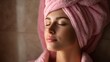 © mila103 - A woman sits quietly with her eyes closed. She has a towel wrapped around her head. The setting has soft lighting and a calm atmosphere suggesting a spa treatment or self care moment.
