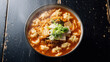 © NYL - A steaming bowl of Korean kimchi sujebi, featuring handmade dough flakes, fermented kimchi, soft tofu slices  in a rich, spicy broth, garnished with scallions.