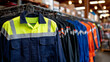 © Maksym Tereshchenko - Wide banner-style shot of a workwear shop interior, rows of road work uniforms and overalls on racks, vibrant safety colors, professional workplace apparel display