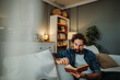 © Dusan - Man relaxing on sofa reading book at home