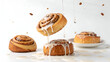 © Criag photography  - Playful dessert composition showing cinnamon rolls floating with icing drips against a minimal white backdrop