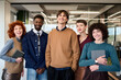 © TrueFrame Collective - Group of diverse young adults standing together in modern office, smiling and looking at camera, including Caucasian women, Black man, Caucasian man, holding digital tablets