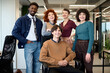 © TrueFrame Collective - Diverse group of young adult men and women posing together in modern office, smiling and looking at camera, representing multiethnic business team collaboration and teamwork