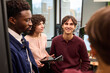 © TrueFrame Collective - Group of young adult multiethnic colleagues discussing project in modern office, Caucasian woman holding digital tablet while Black man and Caucasian woman listening attentively