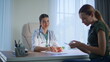 © stockbusters - Woman patient taking pills during medical appointment in health clinic closeup