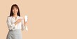 © Pixel-Shot - Asian businesswoman pointing at mobile phone on beige background with space for text