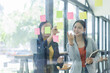 © David - Young businesswoman creative team using post it notes in glass wall to writing strategy business plan to development grow to success.