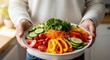 © Olga Ко - Homme végétarien avec une assiette de légumes frais en gros plan.