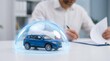 © lianlian liang - Car insurance concept with blue toy vehicle under glowing protective glass dome and businessman signing contract in background. Symbol of auto safety, car loan, warranty, risk management, and liabilit