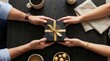 © Viktor - Four hands exchanging a gift box with golden ribbon on a wooden table surrounded by coffee cups and chocolates