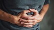 © Sawyer0 - Man clutching his abdomen in severe stomach pain, suggesting cramps and digestive distress.