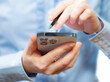 © vizafoto - A woman works with a smartphone in the office, on a report. Close-up of her hands.