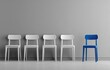 © Fude - Row of white chairs with one unique blue chair against a grey wall