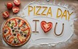 © Muhammad - Delicious homemade pizza with fresh toppings and flour spelling out pizza day i love you on a wooden table with tomatoes and flour