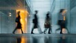 © FauziNh - Blurred figures of professionals walking down a modern corridor with glass walls