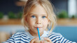© BetterPhoto - Close-up of a young child drinking a smoothie through a straw at home, calm healthy lifestyle moment, hydration and nutrition concept with soft natural light and copy space.