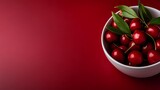 Fresh red cherries with green stems in white ceramic bowl on burgundy background for culinary and food photography projects.