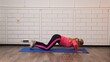 © kinomaster - A woman performs knee push ups on a blue yoga mat, in a gym setting with a white brick wall background.